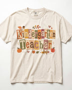 Cream crew-neck short-sleeve T-shirt with “Kindergarten Teacher” fall graphic print