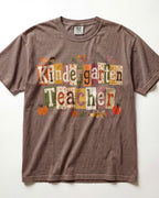 Brown crew-neck short-sleeve T-shirt with “Kindergarten Teacher” fall graphic print