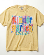 Yellow tan crewneck kids T-shirt with “Kinder Garten Crew” colorful graphic print