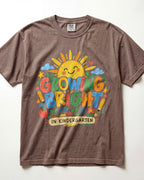 A brown/espresso short-sleeve crewneck t-shirt featuring a colorful graphic on the front with a smiling sun, crayons, stars, and the text 'GROWING BRIGHT! IN KINDERGARTEN'.