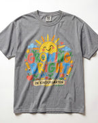 A heather grey short-sleeve t-shirt with a colorful graphic on the front featuring a smiling sun, the words 'GROWING BRIGHT' in playful multicolor letters, and 'IN KINDERGARTEN' on a banner, laid flat against a white background.