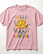 A blossom/pink short-sleeve t-shirt with a colorful cartoon graphic of a smiling sun and the text 'HELLO, LITTLE LEARNERS' surrounded by flowers, stars, and numbers.