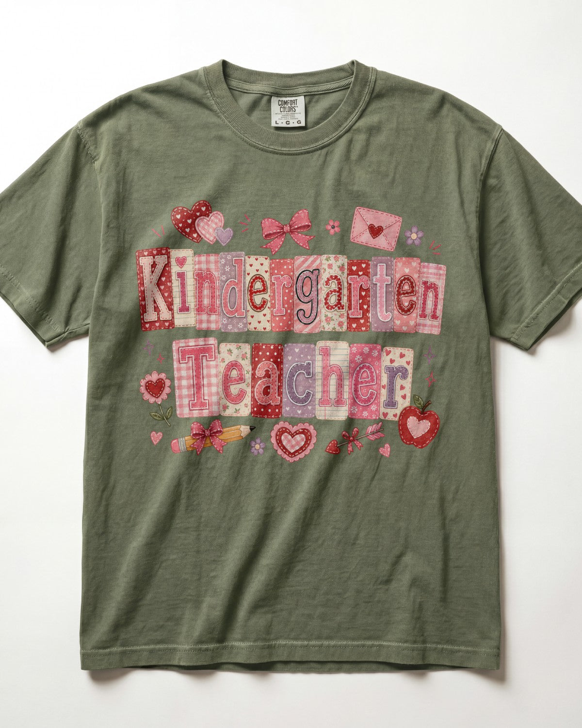 An olive green/moss short-sleeve t-shirt with a 'Kindergarten Teacher' patchwork graphic in pink, red, and purple tones, laid flat against a white background.